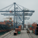 Porto de contêineres em um país asiático sob céu nublado, refletindo a instabilidade econômica global causada pelo conflito no Irã.